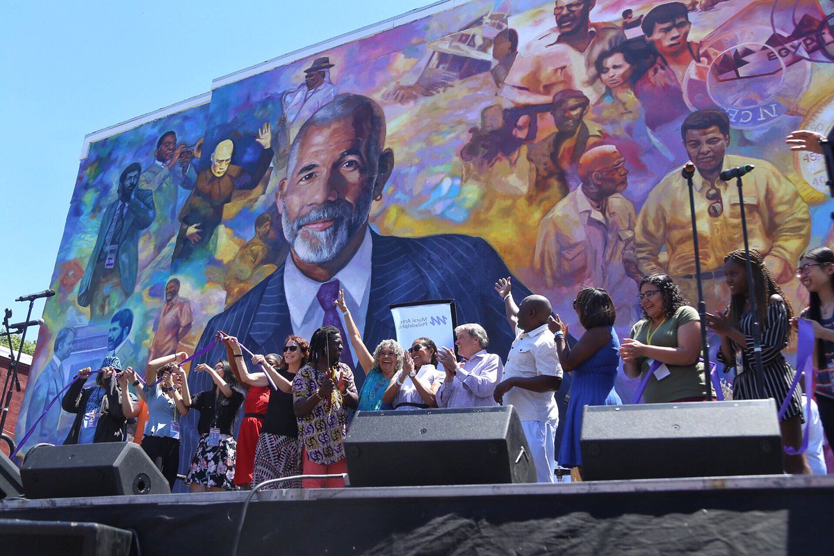 A group of people standing in front of the Ed Bradley mural.
