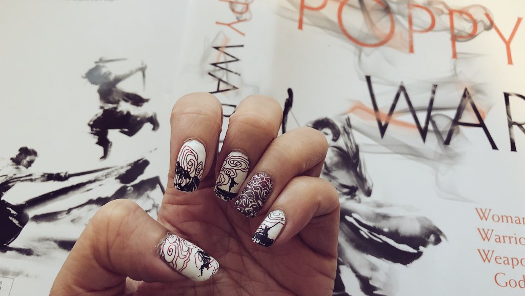Nailart depicting mountains, swirly clouds and silhouettes of martial artists against book cover with similar elements
