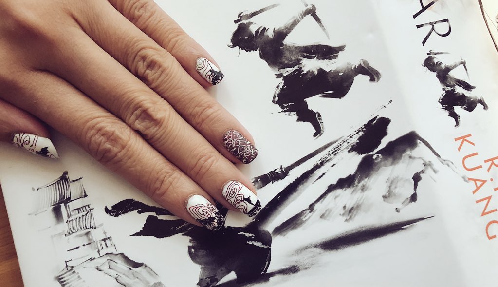 Nailart depicting mountains, swirly clouds and silhouettes of martial artists against book cover with similar elements
