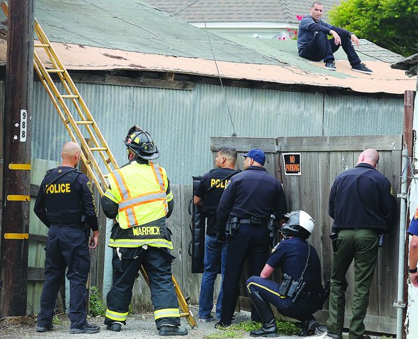 Police from various agencies get help from a Watsonville firefighter in setting up a ladder to help bring a man from the roof of a garage after he reportedly tried to outrun police on foot.