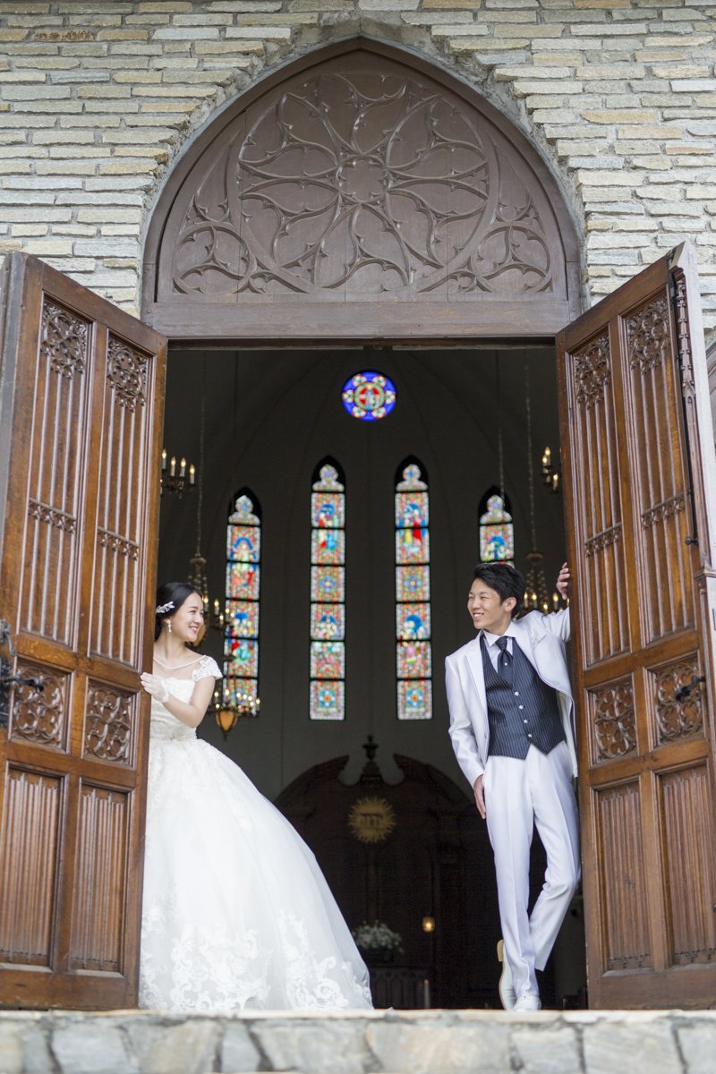 小田原の結婚式場 ベルジュール チャペルのステンドグラスを背景に ２人見つめ合って 太陽の光を浴びて輝くステンドグラスはとっても素敵です バージンロードに色が反射している空間も綺麗ですよ ベルジュール 小田原 結婚式 結婚式場 ステンド