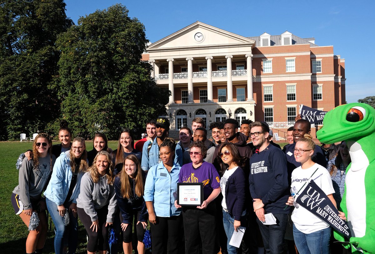 Grace stands in the middle of a crowd of supporters on Ball Circle, holding a framed certificate as she accepts the "Campus Hero" award in Fall 2017.