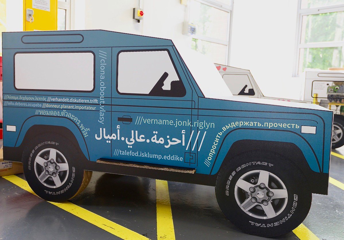 Cardboard cutout of a car with what3word addresses on in different languages