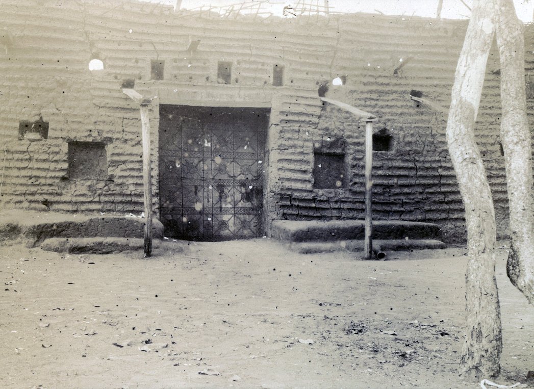 One of the carved doors to the king's compound in Benin City, ruined after the looting and burning of Benin by the British, c. 1897-1898. Pitt Rivers Museum.