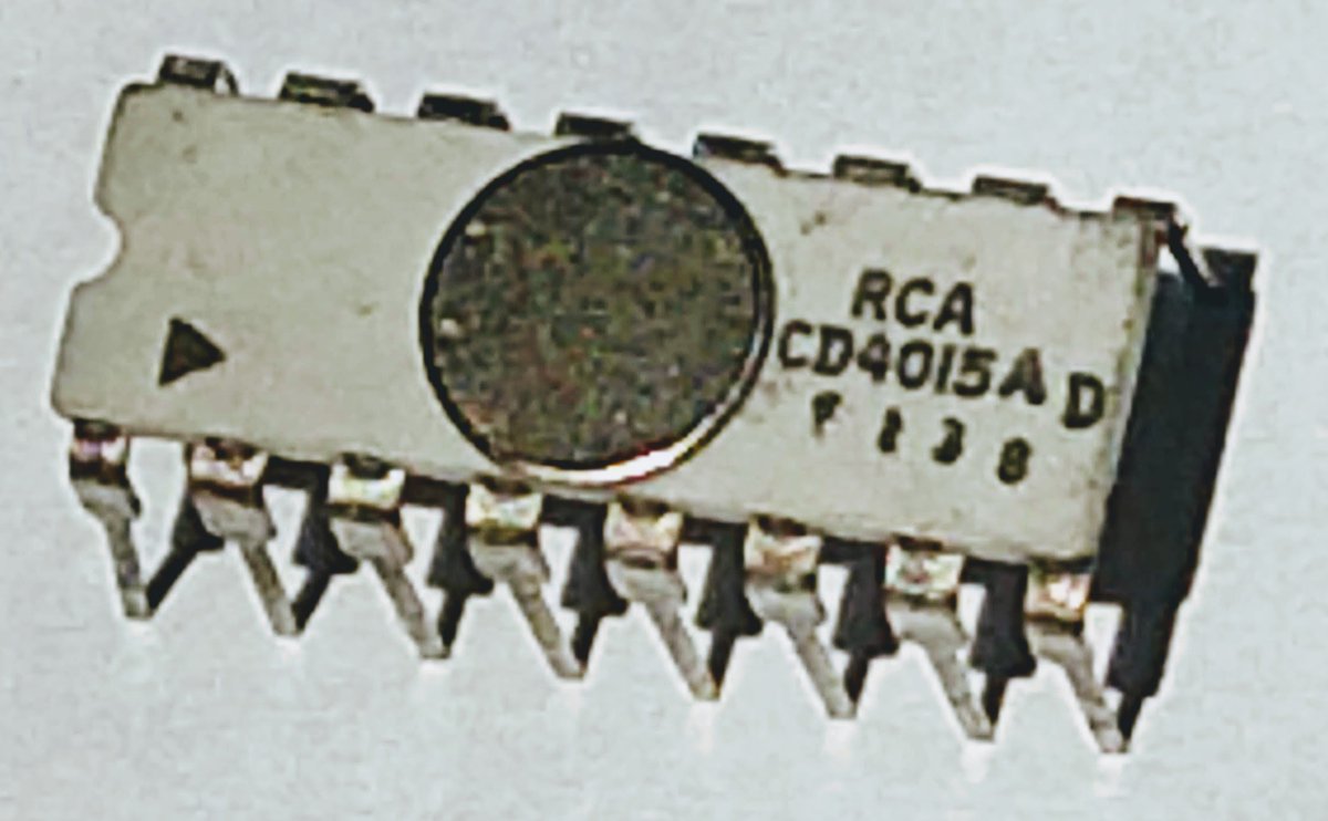 An old integrated circuit with 16 pins and an unusual circular metal lid in the middle. The chip is labeled "RCA CD4015A".