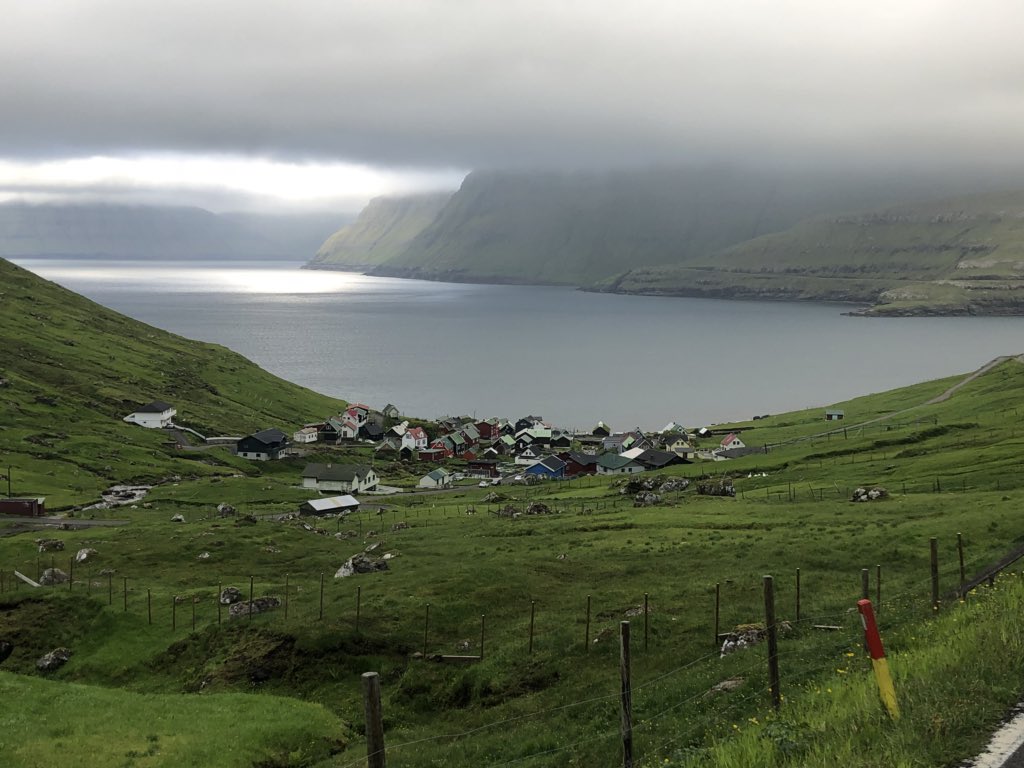 ThePerfectSpot's tweet photo. Each village sparsely situated around the green wilds of the #FaroeIslands has a story. And each is situated in unique configurations, like this village near our town of Elduvík, nestled at the base of a steep mountain road with hairpin turns. #Funningur #Eysturoy #Travel https://t.co/RcQ2cMdBAx