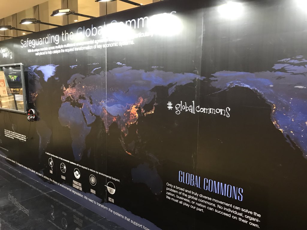 Large, high-resolution map of the earth at night, with hand-drawn systems icons and #globalcommons in white