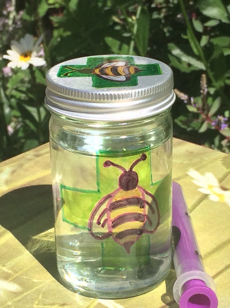 A small glass jar with an illustration of a bee in a garden
