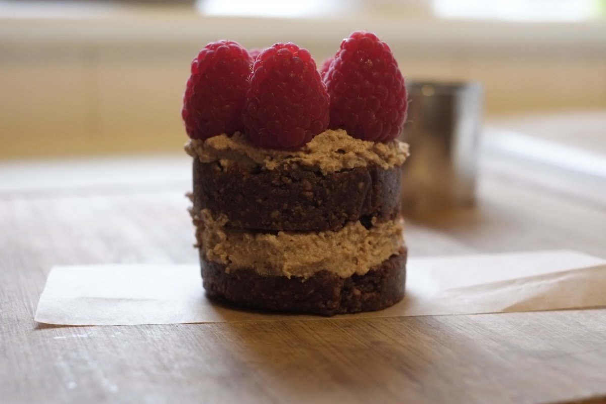 Raw chocolate cake with nut cream and fresh raspberries, sweetened with dates