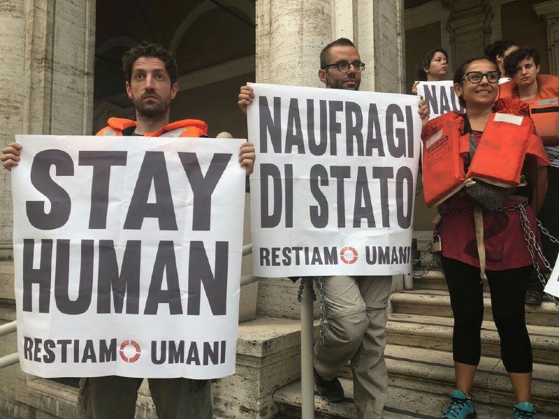 Nonostante il caldo e la polizia che rifiuta di far passare dell'acqua, gli attivisti rimangono incatenati al ministero per denunciare i #naufragidistato. Tanta gente sta accorrendo per portare solidarietà e s'invita ad andare al ministero delle Infrastrutture #RestiamoUmani