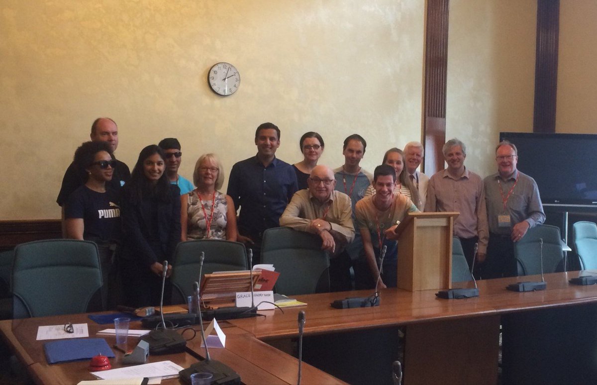 Large group in Glasgow City Chambers standing in front of a yellow wall.