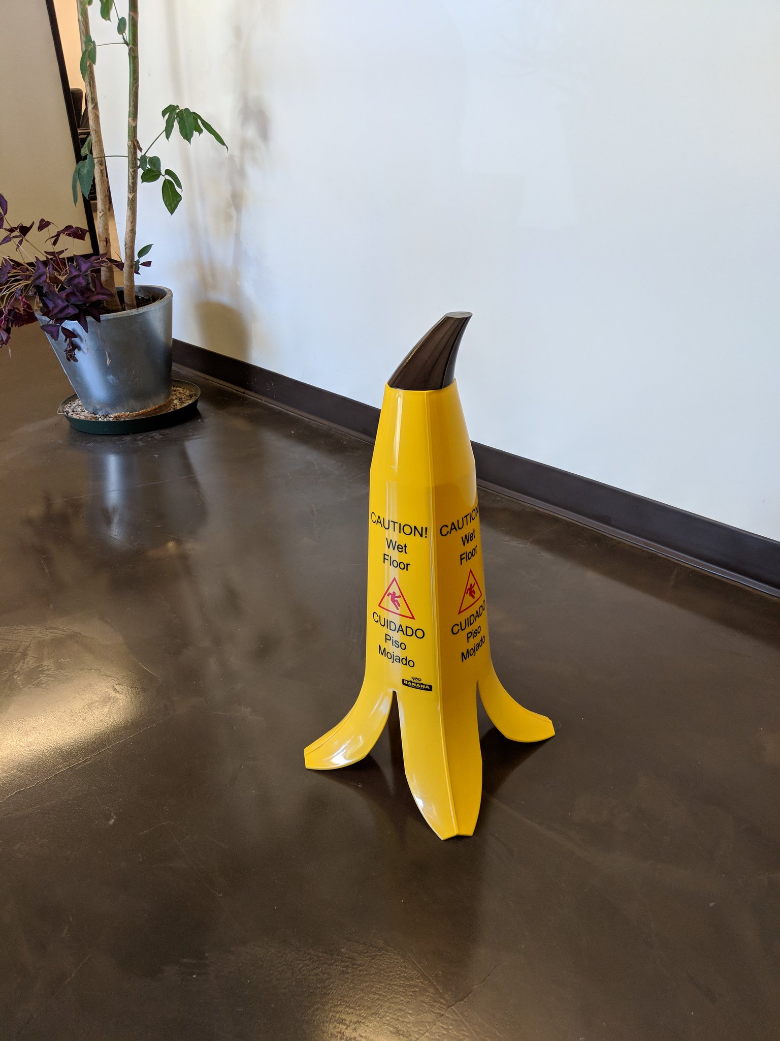 A Caution! Wet Floor sign in the shape of a banana peel. 🍌