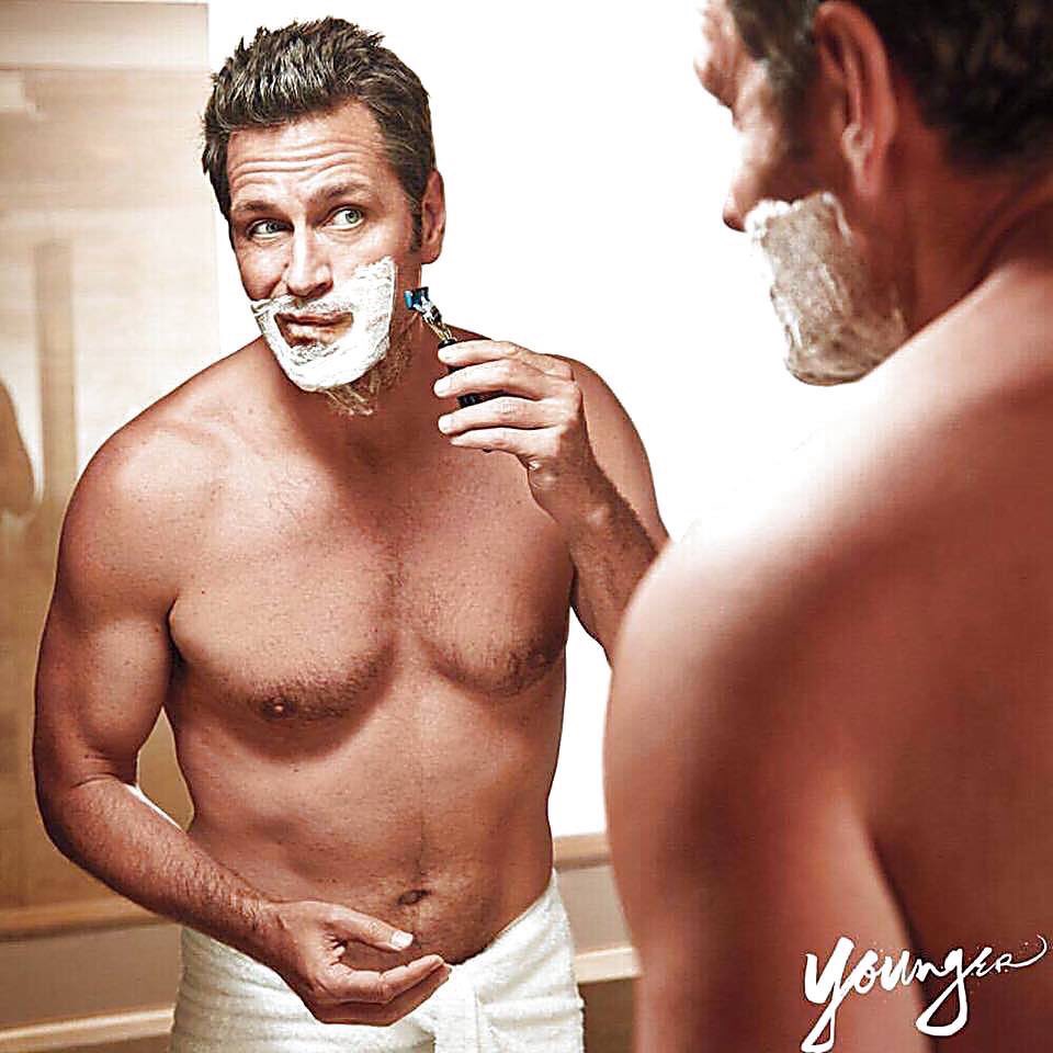 Peter Hermann shaving shirtless. 
