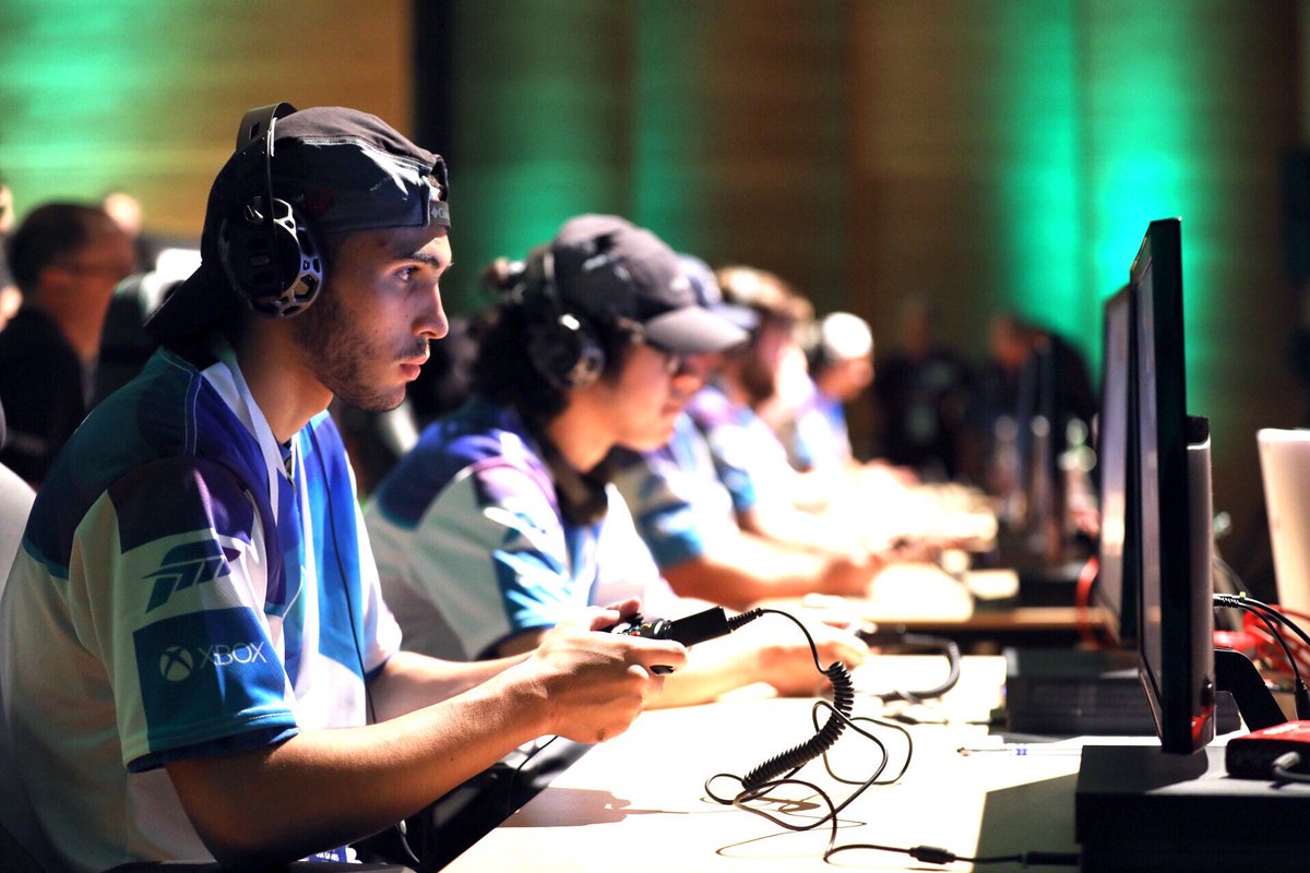 Photo of gamers holding controllers and looking ahead at screens