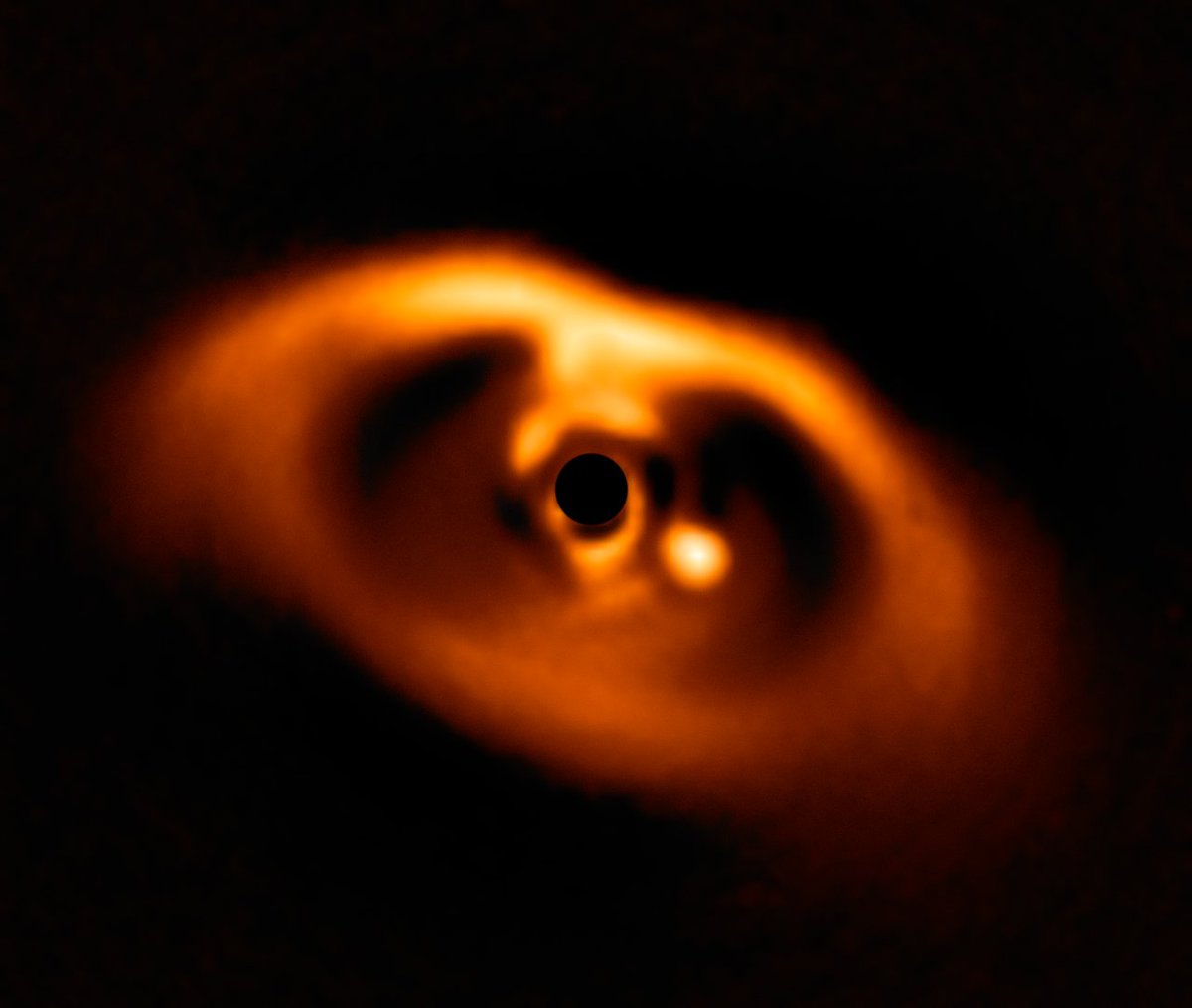 Cmdr_Hadfield's tweet photo. That yellow blob is a newborn planet in another solar system - it's absorbing the disc of dust around the very young blacked-out star in the middle. Amazing to see! https://t.co/wKPUiqaIIC @ESO https://t.co/rJJOnfF6iv