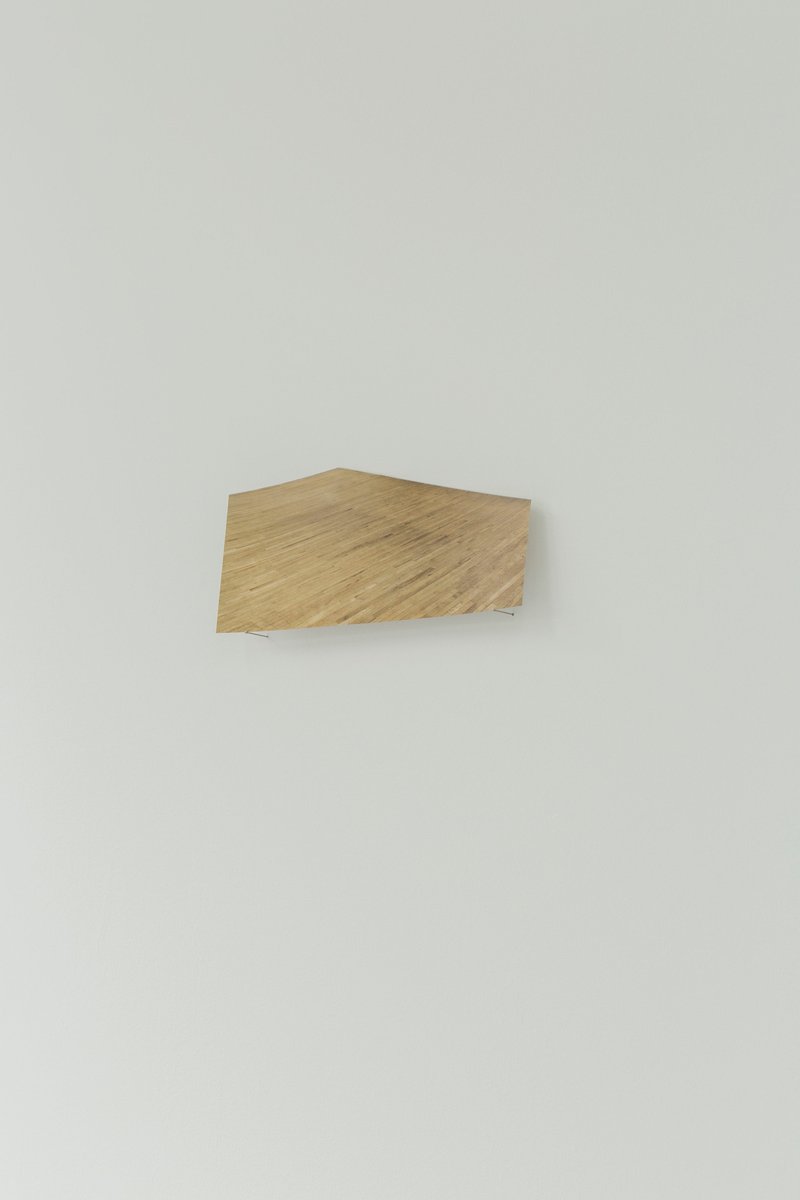 Floor (2018) an image of a wooden floor is mounted on two pins at an oblique angle, resulting in a playful punctuation with the wall's spatiality.