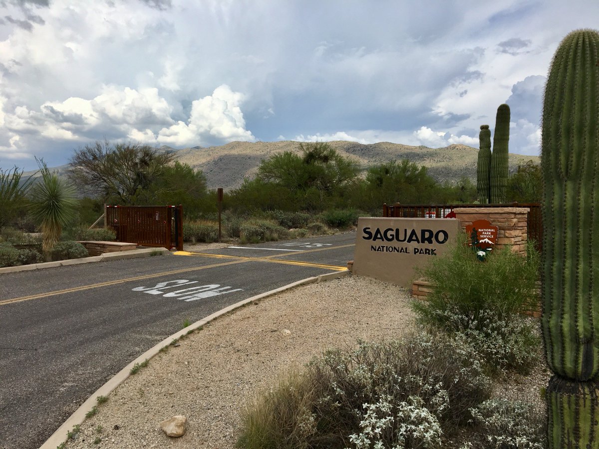 Monsoon storm clouds are visible behind the Saguaro National Park Entrance Sign
