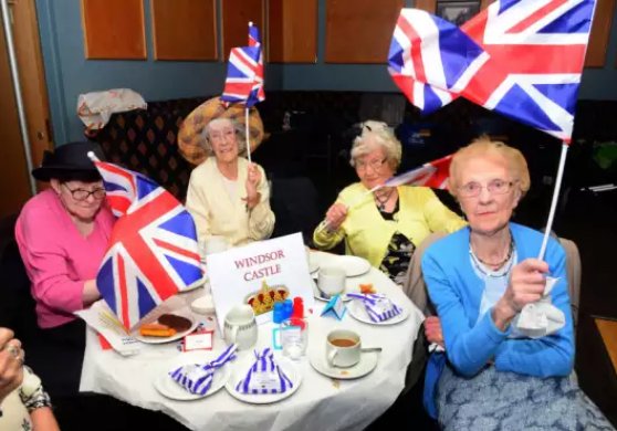 Old ladies with union flags having afternoon tea