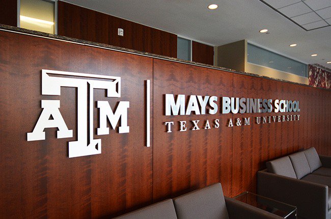 Texas A&M logo and "Mays Business School" in silver letters on a wood wall inside the Wehner Building