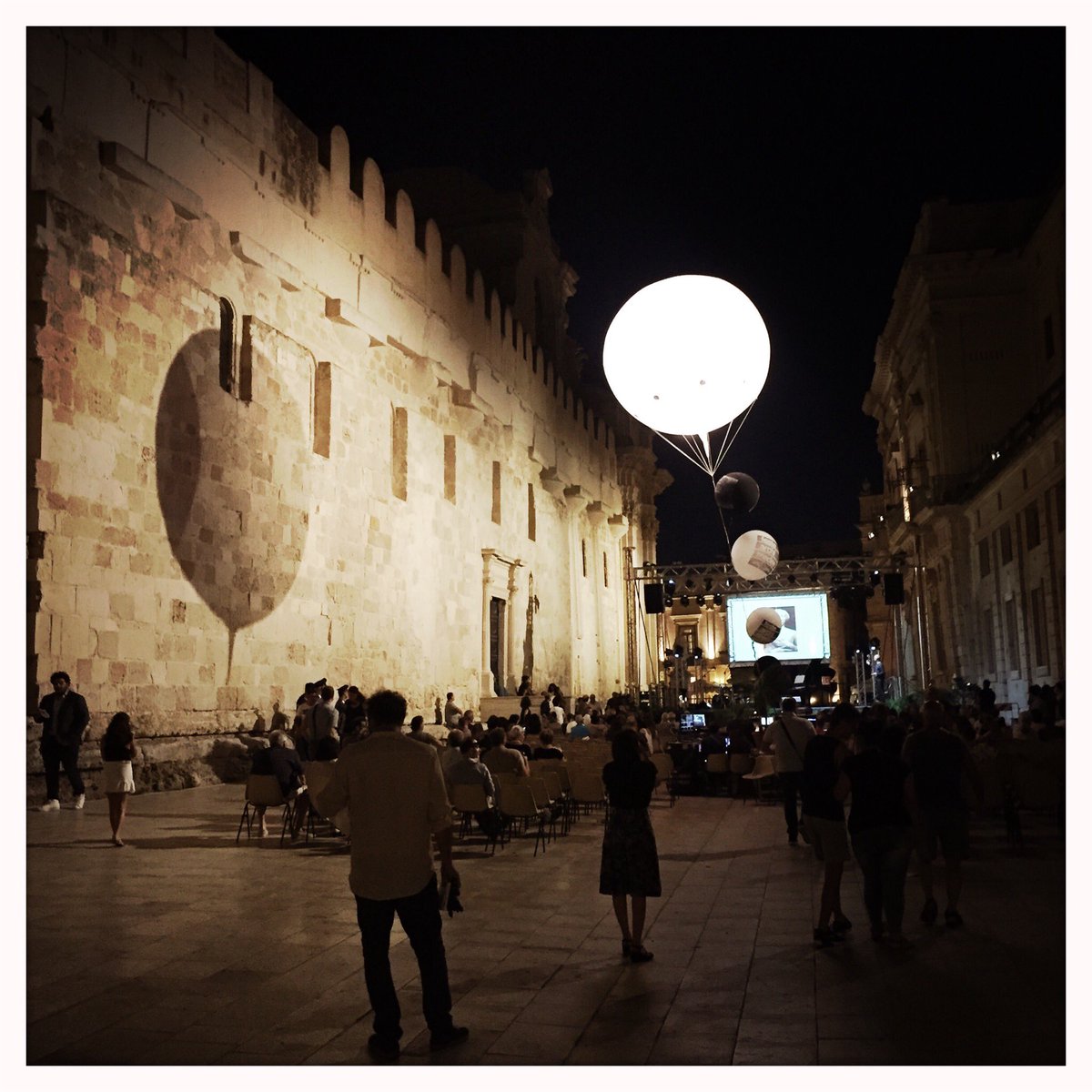 KeathParker's tweet photo. recipe:
1. close street.
2. install large lit helium balloon.
3. add stage, lighting, seating.
4. find lecturer to speak (on art).

result: irresistible and engaging public space.
#siracusa #sicily https://t.co/jU8Ulfu6NV
