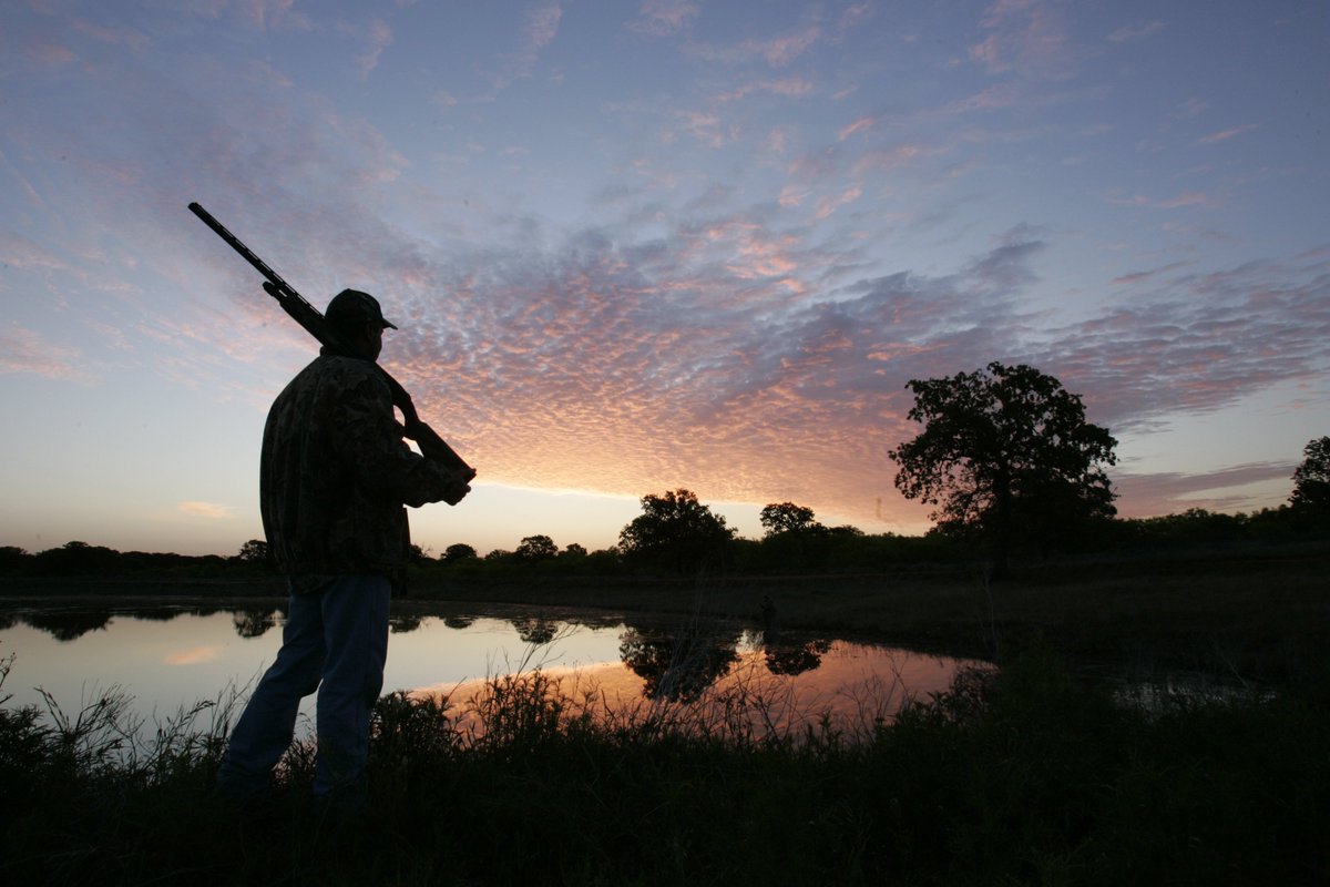 Hunter overlooking lake at sunrise