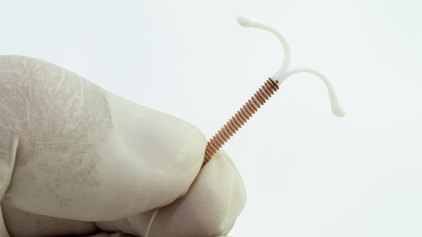 Closeup of gloved fingers holding a long-acting reversible contraceptive device, or LARC