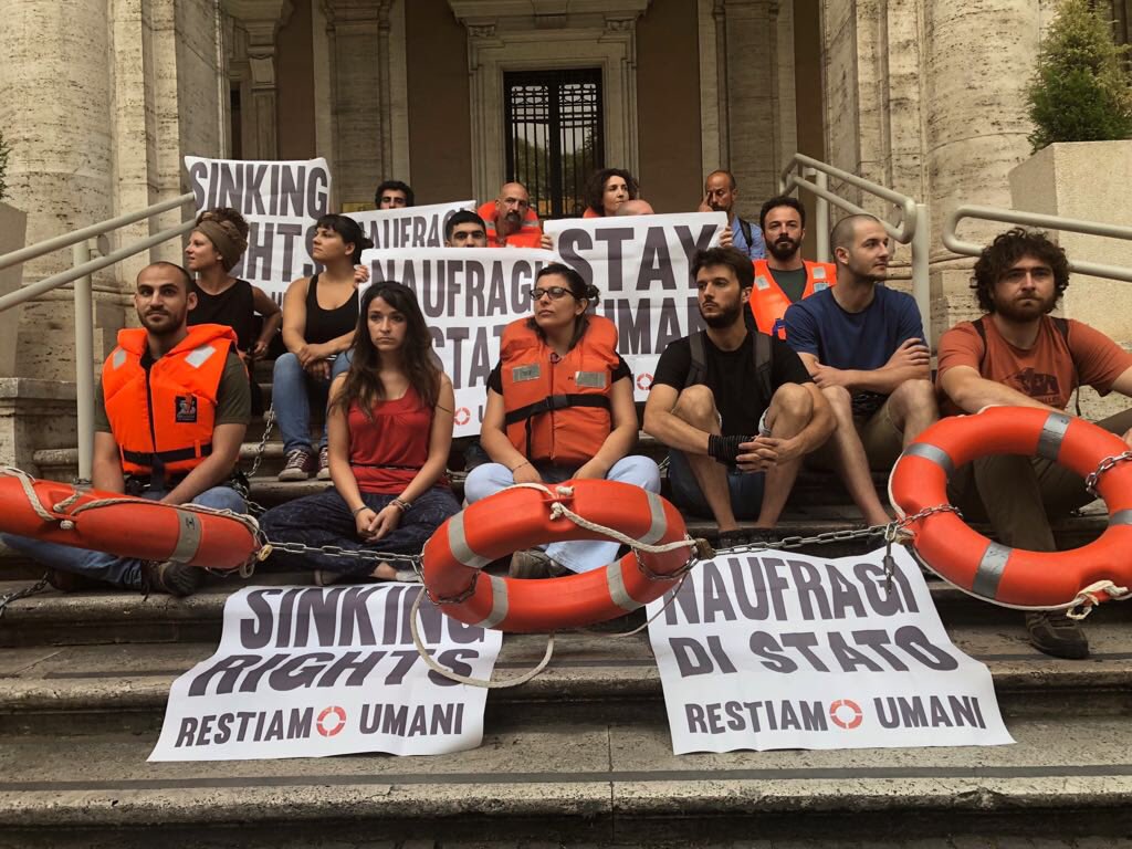 Greenpeace_ITA's tweet photo. Gli attivisti vestono giubbetti di salvataggio e salvagenti per ricordare alle Istituzioni che non possono essere complici dell’omissione di soccorso #RestiamoUmani #NaufragiDiStato https://t.co/K341Zbzdul