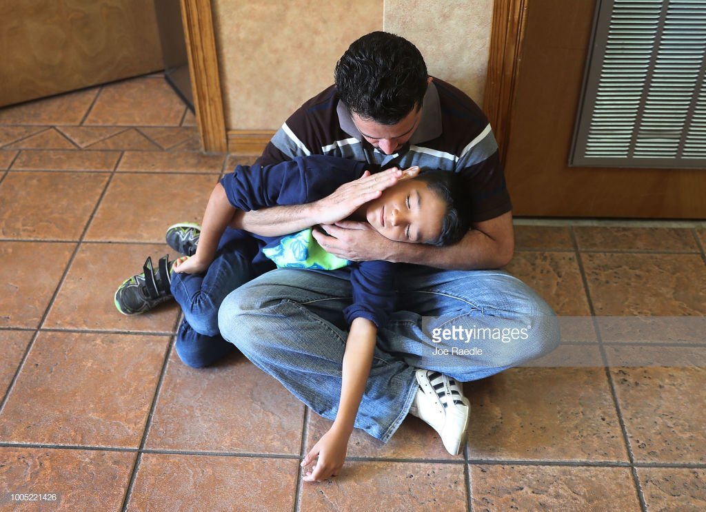 EL PASO, TX - JULY 25: A man, identified only as Renan, spends time with his son, Nathan,11, as they are cared for in an Annunciation House facility after they were reunited with each other on July 25, 2018 in El Paso, Texas.