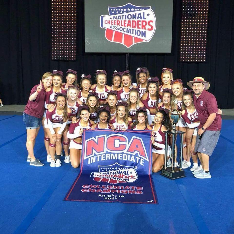 cheer team posing with championship banner and trophy