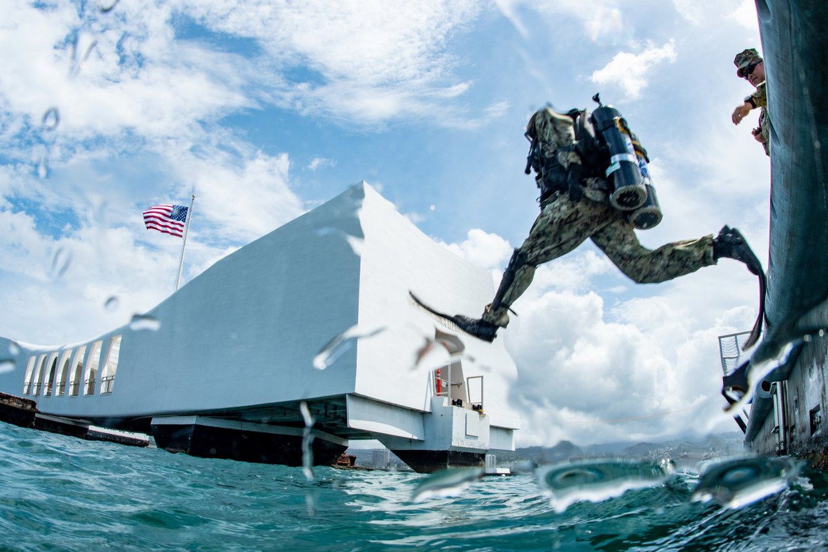 A U.S. Navy sailor in diving gear is shown just before entering the water next to the USS Arizona Memorial at Pearl Harbor.