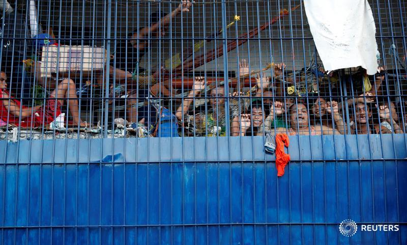 Detainees look out from a cell at a police station in the Philippines