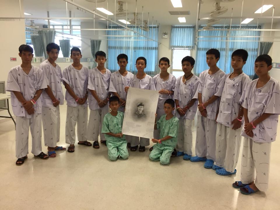 13 #ThamLuang survivors and the portrait of the late ex-Thai Navy SEAL diver Saman Kunan, on which they penned their messages for him. (Photo: Thai Public Health Ministry)