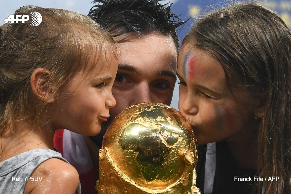 afpfr's tweet photo. #CM2018 Le capitaine Hugo Lloris et ses filles embrassent le trophée #AFP https://t.co/4cTrISKYFi