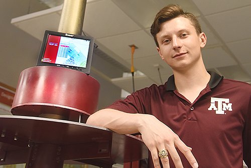 student leaning against equipment wearing Texas A&M polo