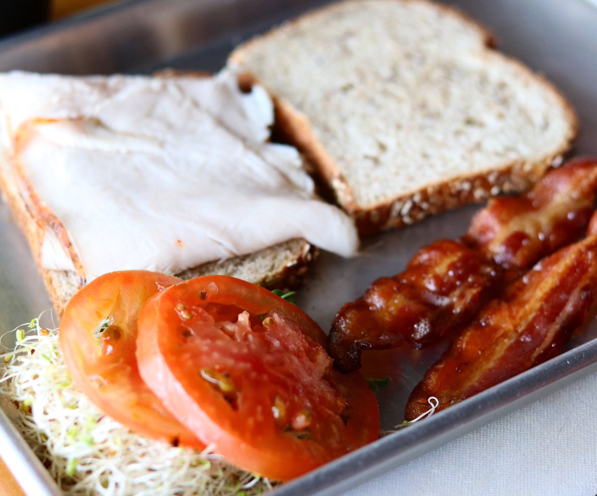 It’s lunch time! Come enjoy our tasty turkey club — roasted turkey, bacon, fresh local tomatoes, and sprouts served with our housemade garlic mayo on seeded bread. 🥓 🍅