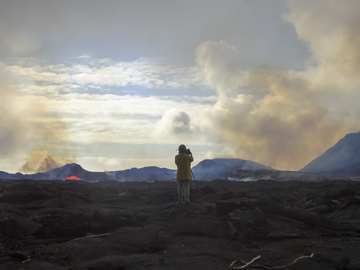 USGS field crews monitor Kīlauea Volcano's lower East Rift Zone eruption around the clock. Here, a scientist takes video of lava as it exits the fissure 8 cinder cone. The video helps document lava flow behavior, including flow velocity and cooling characteristics, as well as changes to the lava channel.