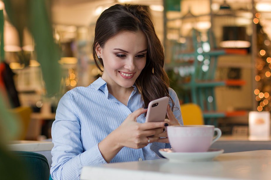 woman on phone smiling with her coffee nearby
