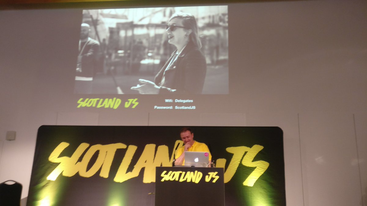Peter on stage behind a podium, with the Scotland JS banner