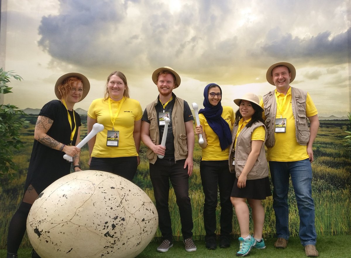 Five people dressed in explorer hats, with a huge Dino egg with a scenic background