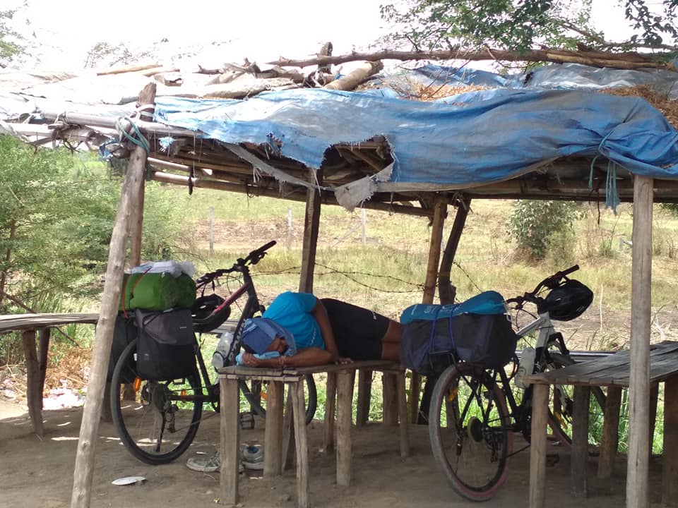 A man sleeping below a shade. Two cycles are visible