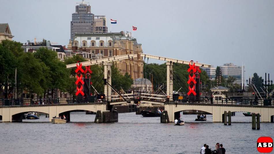 photodam's tweet photo. Had je deze al gezien? 
De Magere Brug vraagt aandacht voor het AIDS congres in RAI.
#AIDS2018 #skinnybridge #amsterdam
Meer?
https://t.co/s8PorpvoE5 https://t.co/r8QAuvEhBO