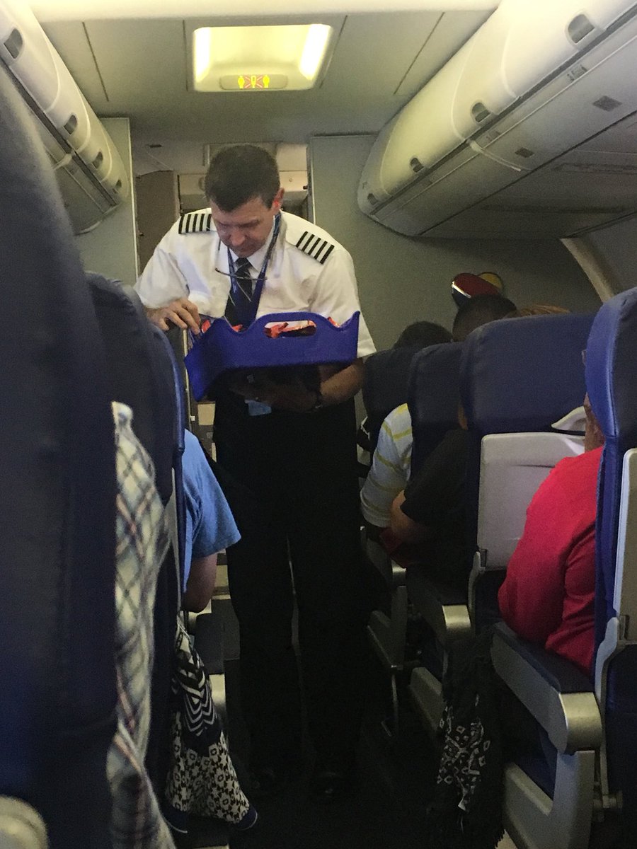 A <a href="/SouthwestAir/">Southwest Airlines</a> copilot serving snacks to the customers. Teamwork makes the dream work! #CustomerService