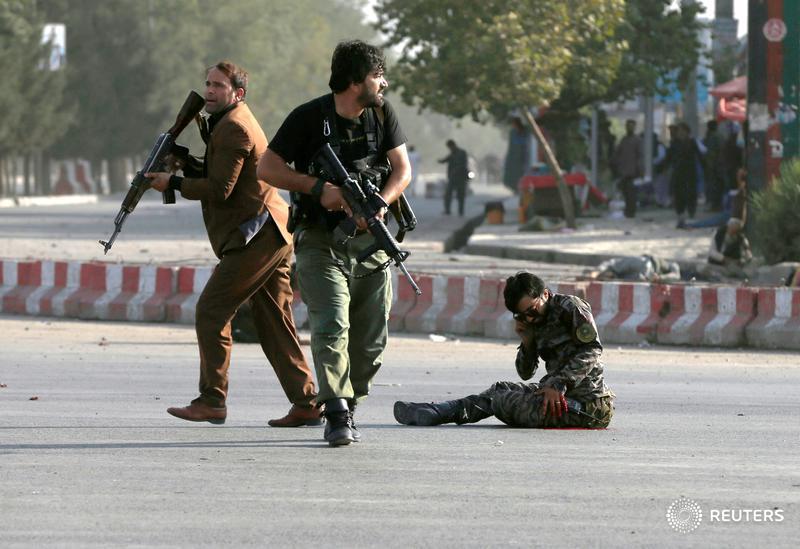 Members of Afghan security forces arrive as an injured man sits on the ground at the site of a blast in Kabul.