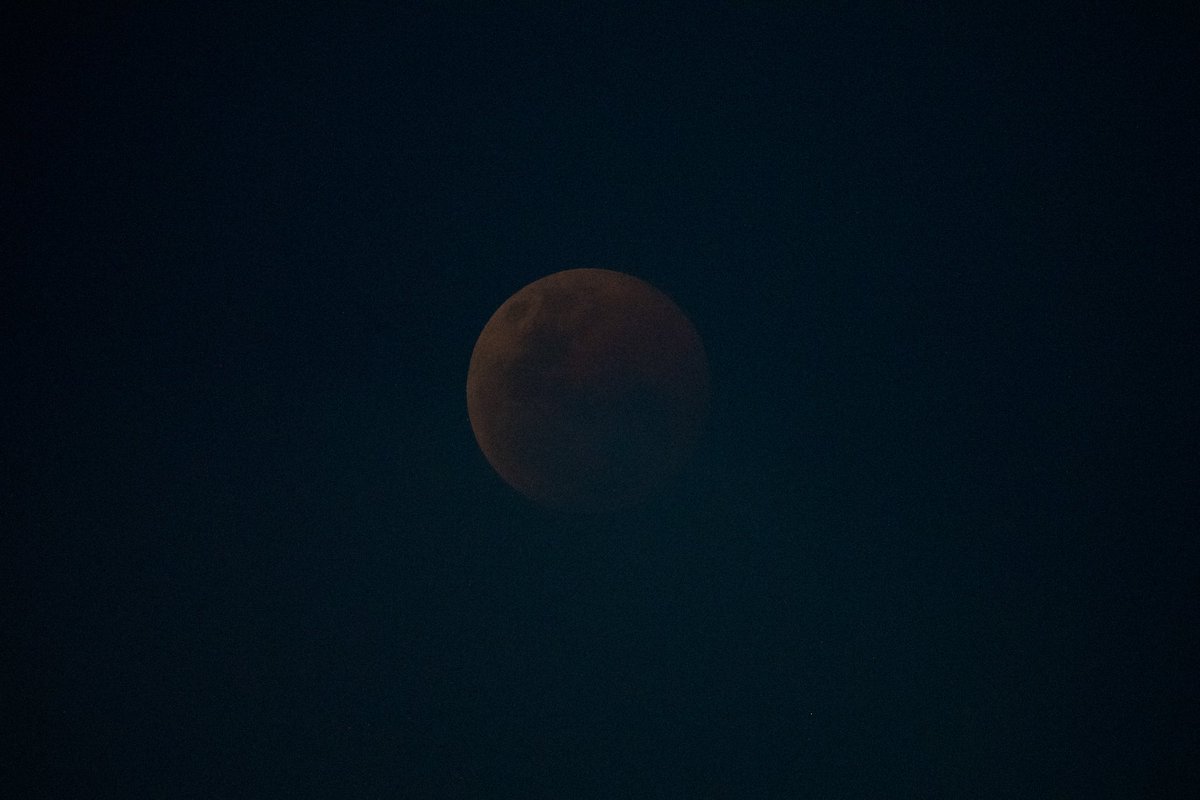 Astro_Alex's tweet photo. Just took a photo of the #LunarEclipse from the @Space_Station. Tricky to capture. The slight hue of blue is actually the Earth's atmosphere, just before the Moon is "diving into it".  #Horizons https://t.co/X8r7puloQl