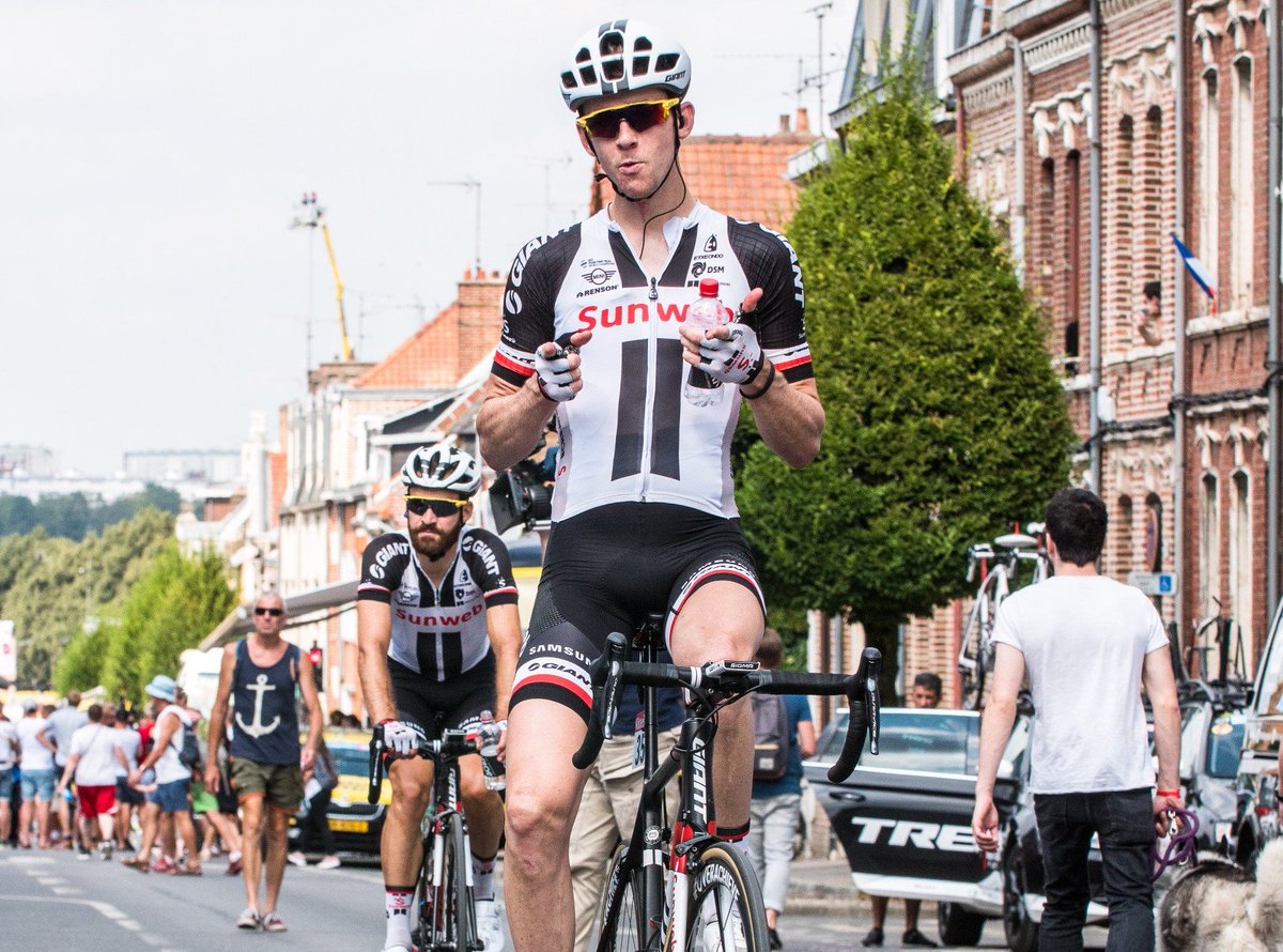 Chad Haga sitting up on his bike pointing his fingers at the camera after completing the race