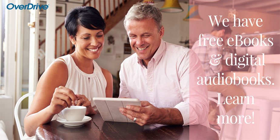 a photograph of two people, one man one woman, both reading from the same tablet and smiling