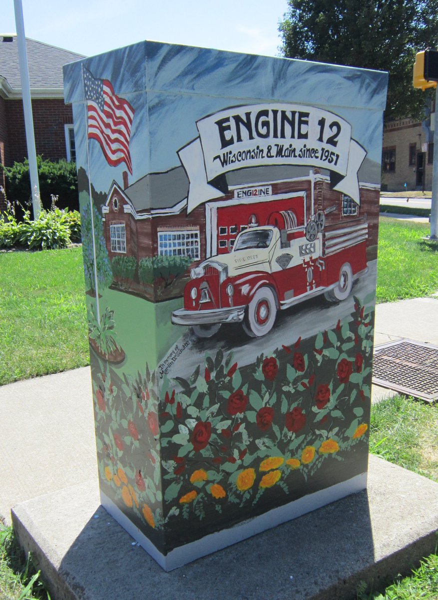 NorthWinton's tweet image. Check out the traffic box at East Main &amp;amp; Wisconsin!

Artist Elsie Taylor Cleary is pictured next to the captain of Engine 12 &amp;amp; a fireman with her tribute to our neighborhood’s firefighters, including the original fire truck from 1951 and the Engine 12 logo on the back. @IAFF1071