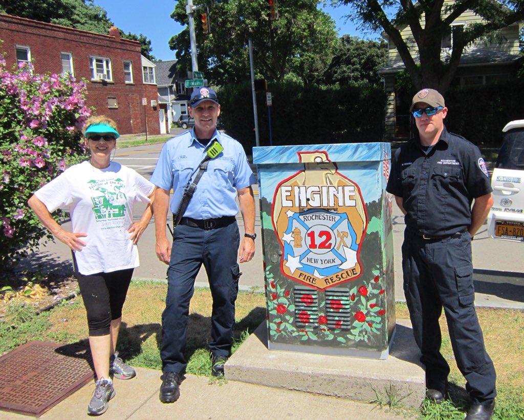 NorthWinton's tweet image. Check out the traffic box at East Main &amp;amp; Wisconsin!

Artist Elsie Taylor Cleary is pictured next to the captain of Engine 12 &amp;amp; a fireman with her tribute to our neighborhood’s firefighters, including the original fire truck from 1951 and the Engine 12 logo on the back. @IAFF1071