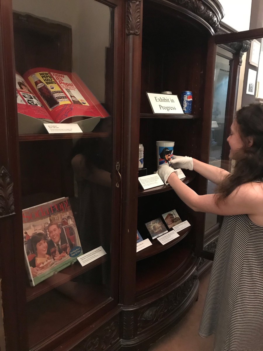 NCCollection's tweet photo. Our NCC Gallery student worker, Hannah Frish, is putting the final touches on our new #Pepsi focused exhibit for North Carolina's original soda turning 120 years this month.  Come check it out next time you are in @WilsonLibUNC! https://t.co/Ml9aDZieqR