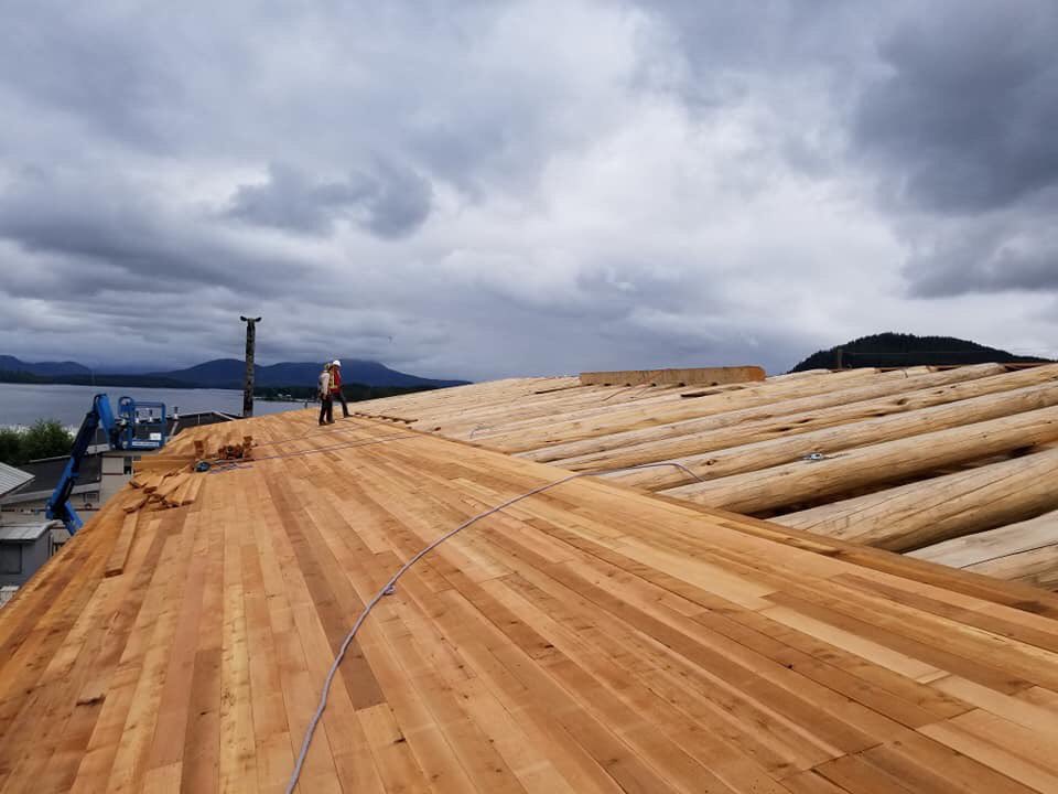 HeiltsukBH's tweet photo. The north side of the #HaíłzaqvBighouse now has half a roof, and the south side is already done. The goal is to have the house tightened up before the fall weather sets in! Photo Credit: Eddie Jones https://t.co/iA8SwhyuO7